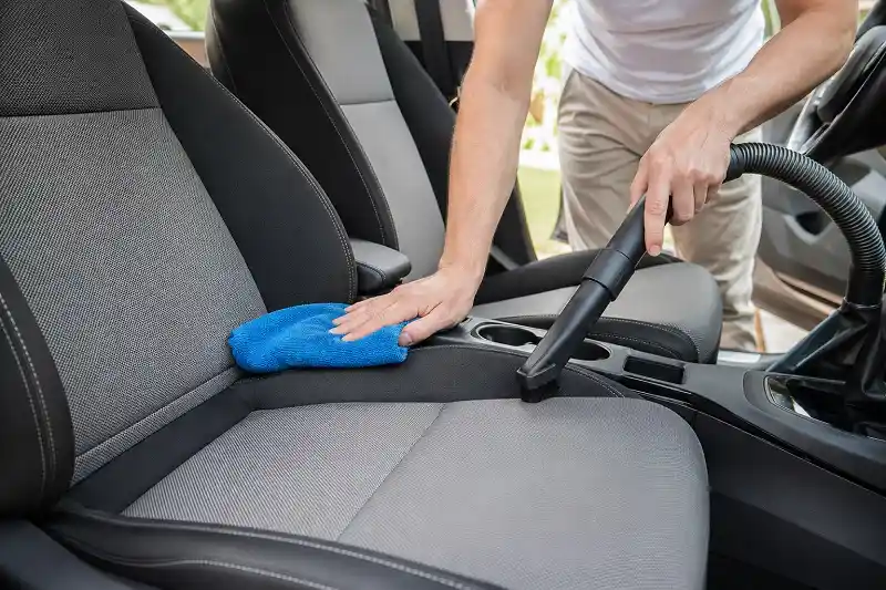 a man vacuuming a car upholstery